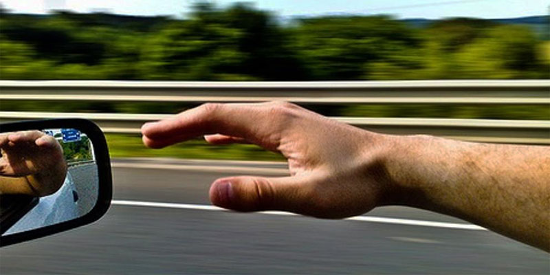 Hombre con el brazo sacado por la ventanilla de un coche