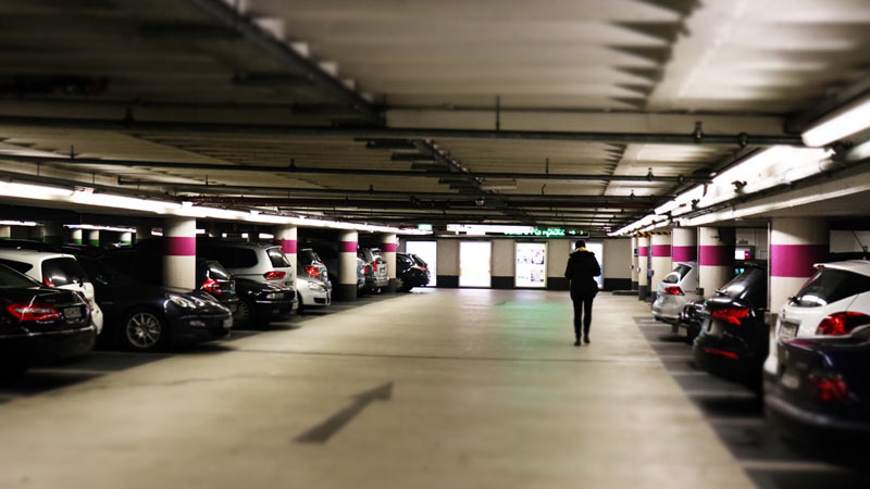 Parking de un centro comercial con varios coches aparcados y un señor andando