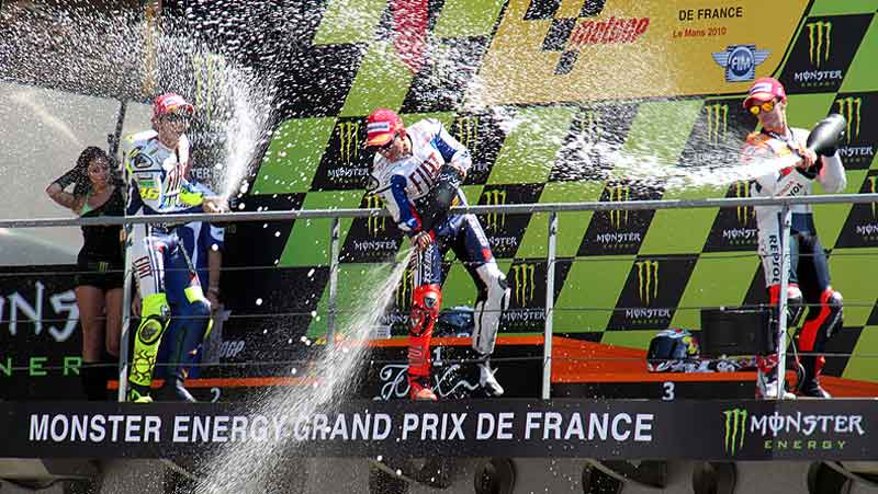 Pilotos de Moto GP tirando champán desde el podio